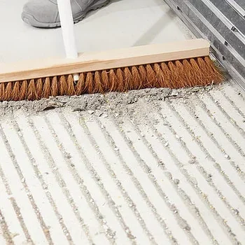 Ansicht eines verschmutzen Mattenboden mit Einsatz eines Besens